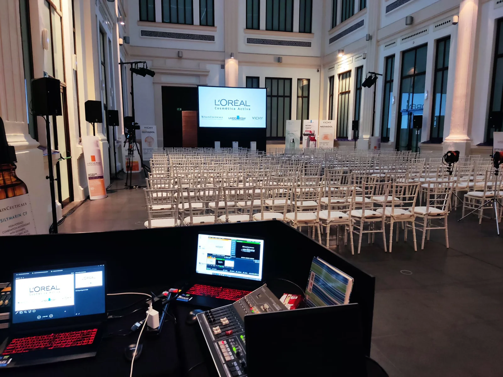 Control técnico con monitores y sala preparada para un evento corporativo